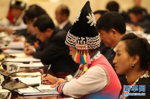 A delegate wearing a traditional ethnic minority costume takes notes at the panel discussion of delegates from southwest China's Yunnan Province on November 9, 2012, during the 18th CPC National Congress. [Xinhua]