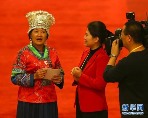 Delegate to the 18th CPC National Congress and primary school teacher from southern China's Hunan Province Chao Hong (L) wears her Miao ethnic minority costume. She sings a local folk song during an interview on November 9, 2012. [Xinhua]