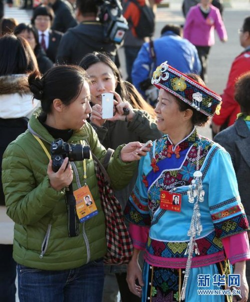 Delegate to the 18th CPC National Congress and judge from Tongchuan Intermediate People's Court in southwest China's Guizhou Province Yang Xia (R) wears her ethnic minority costume while giving an interview at Tian'anmen Square on November 8, 2012. [Xinhua]