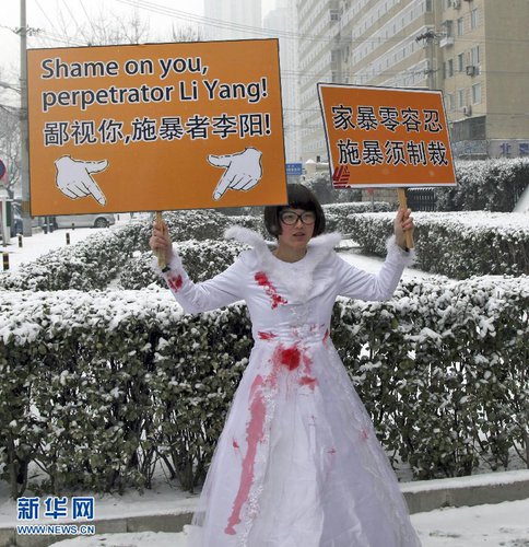 One of Kim Lee's supporters holds up a placard with statements against domestic violence outside the Chaoyang District People's Court. [Xinhua]