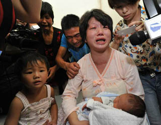 Lai Guofeng's wife holds her baby rescued by police in Fuping, Shaanxi Province, on August 5, 2013. [Xinhua]